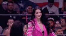 a woman in a pink jacket is standing in front of a crowd at a wrestling match .