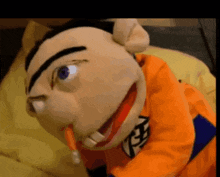 a puppet is wearing an orange shirt with a dragon ball z logo
