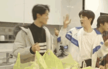 a group of young men are standing in a kitchen and one of them is wearing a jacket that says " reebok " on it