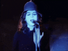 a woman singing into a microphone while wearing a hat