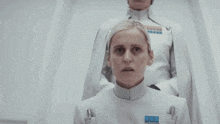 a woman in a white uniform with a blue badge on her chest