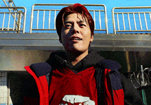 a man wearing a red jacket and a black hoodie