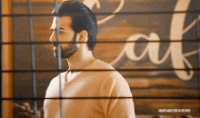 a man with a beard stands in front of a sign that says cafe