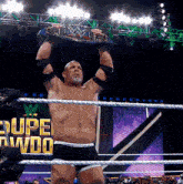 a man in a wrestling ring holding a wwe championship belt over his head