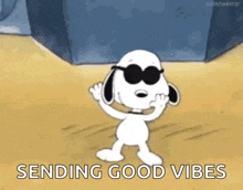 a cartoon of snoopy wearing sunglasses and waving with the words `` sending good vibes '' below him .