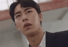 a young man in a suit and tie is making a surprised face .