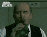 a man in a white shirt and black vest is laying down with the words white walkers above him
