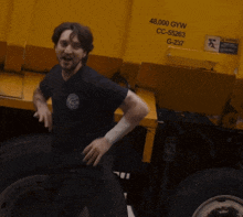 a man is standing in front of a yellow dumpster that says 48,000 gyw cc-55263 g-237