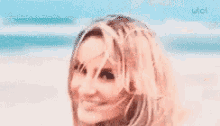 a woman in a white dress is smiling on the beach .