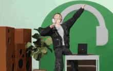 a person wearing headphones is dancing in front of a laptop and speakers