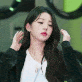 a woman adjusts her hair while wearing a white shirt