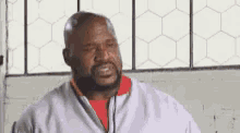 a man with a beard and a white jacket is sitting in front of a window in a room .