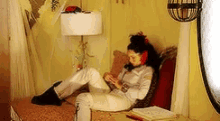 a woman sits on a couch in a room with a lamp