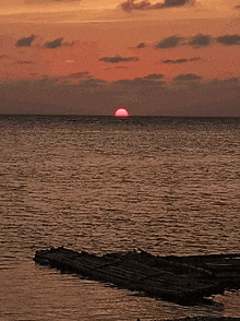 a sunset over a body of water with a wooden platform in the foreground