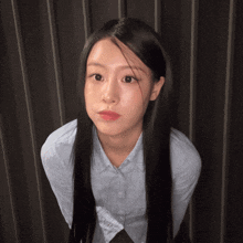 a woman with long black hair wearing a light blue shirt