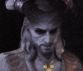 a man with horns and a beard is wearing a necklace with gold coins on it