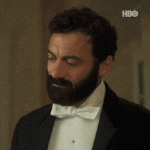 a man with a beard and a bow tie is wearing a tuxedo .