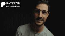 a man wearing glasses and a grey shirt with the words " patreon cap bailey asmr " on the bottom
