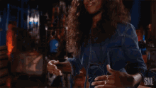 a woman in a denim jacket is dancing on a stage .