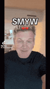 a man in a black shirt has the word smyw on his head