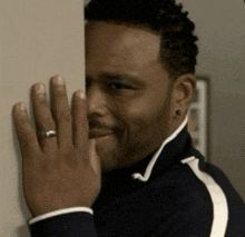 a man with a ring on his finger is peeking over a wall