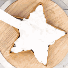 a star shaped cookie covered in white frosting on a wooden cutting board