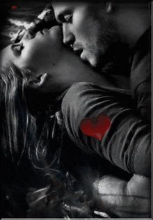 a man kissing a woman with a red heart on her shirt