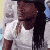 a man with dreadlocks wearing a hat and a white shirt