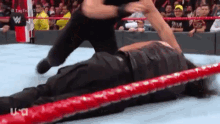 a wrestler is laying on top of another wrestler in a wrestling ring during a match .