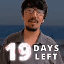 a man with glasses and a beard is standing in front of a sign that says 19 days left