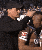 a man is putting a medal around a man 's neck who is wearing a jersey with the letter g on it