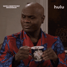 a man in a red robe is holding a cup of coffee in front of a hulu ad