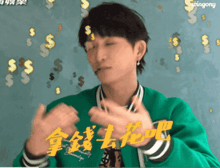 a man in a green jacket is clapping in front of a wall with pingony written on it