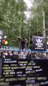 a man is doing a trick on a skateboard in front of a sign that says hkamerica.com