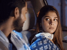 a man and a woman are looking at each other in a car .