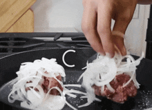 a person is putting onions into a frying pan with the letter c visible