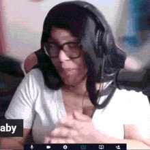 a woman wearing glasses and headphones is sitting in front of a sign that says aby