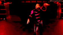 a wrestler is standing on a stage in front of a red background .
