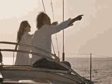 a man and a woman are sitting on a boat pointing at the ocean