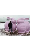 a man stands in front of two large pink bunny statues