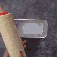a person is using a rolling pin to roll a piece of dough into a pan