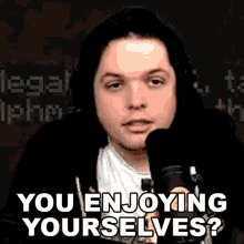 a man in headphones is sitting in front of a microphone and saying `` you enjoying yourself ? ''