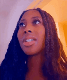 a close up of a woman with braids making a funny face while looking up .