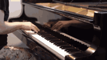 a person playing a yamaha grand piano with their hands on the keys