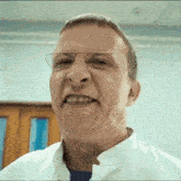 a close up of a man wearing glasses and a white coat making a funny face .