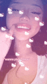 a girl with hello kitty stickers on her face is smiling and says " wanna play roblox "