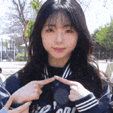 a young girl is making a heart shape with her fingers .