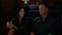 a man and a woman sitting on a couch holding glasses
