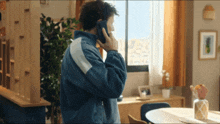 a man in a blue jacket is talking on his cell phone