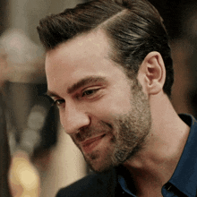 a man with a beard wearing a blue shirt smiles